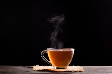 A Cup of freshly brewed black tea,escaping steam,warm soft light, dark black background