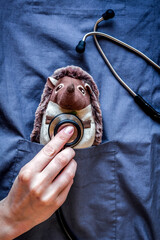 stethoscope, hedgehog toy in children's doctor pocket blue background top view mock-up