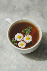 Cup of herbal tea with chamomile flowers and mint leaves