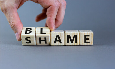 Blame or shame symbol. Businessman turns wooden cubes and changes the word 'shame' to 'blame' or...