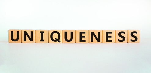 Inclusiveness and uniqueness symbol. Wooden cubes with the word 'uniqueness'. Beautiful white background. Business, inclusiveness and uniqueness concept. Copy space.