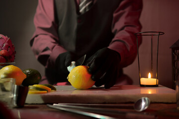 Professional bartender preparing drink with ice and fruits