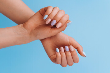Stylish fashionable female manicure. Beautiful hands of a young woman on blue background.