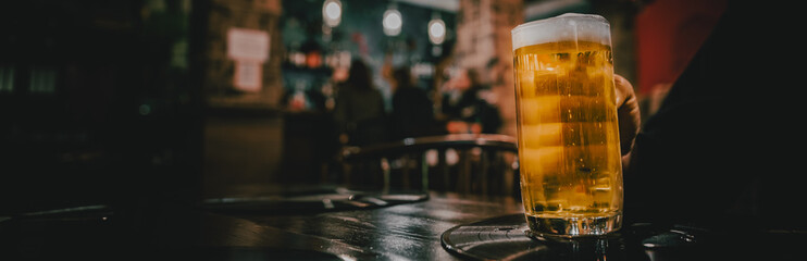 man hold a glass of beer in his hand at the bar or pub