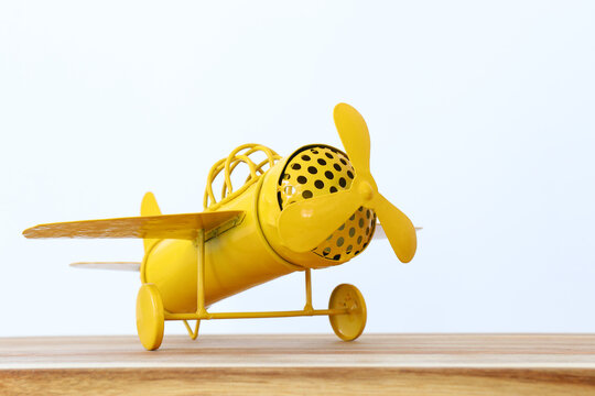 image of retro yellow metal toy airplane over wooden table