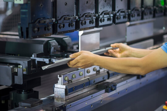 The technician operator working with hydraulic press brake bending machine. The sheet metal working operation by skill operator.