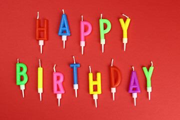 Colorful happy birthday candles on a red background