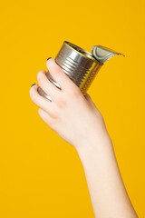 Hands hold recycling used cans,  metal objects isolated on yellow background. Stop nature garbage,...