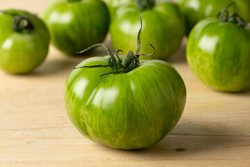Whole fresh green zebra tomato close up and tomatoes in the background 