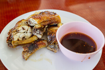Grilled chicken in a plate and dipping sauce in a cup.