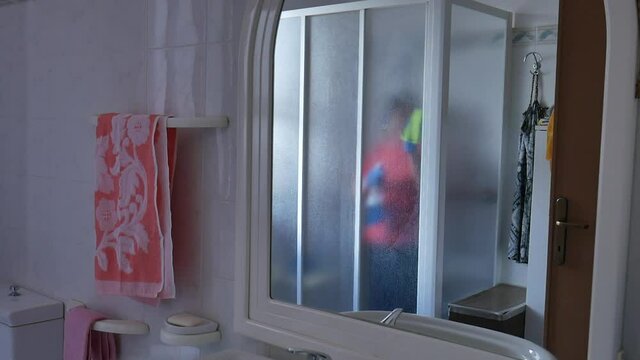woman sanitizing shower box windows with blue bactericidal spray against viruses