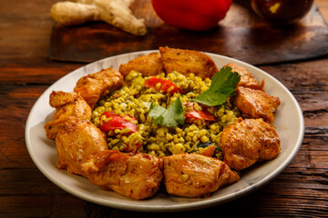 Food for suhoor in Ramadan bulgur post with beef in a plate on a wooden table next to vegetables on a board.