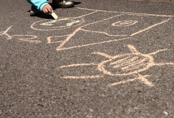 child draws pictures with chalk on the asphalt