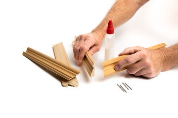 craftsman's hands getting ready to glue molding to make a picture frame isolated on white