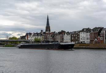 river barge travels upriver on the Maas River in downtown Maastricht