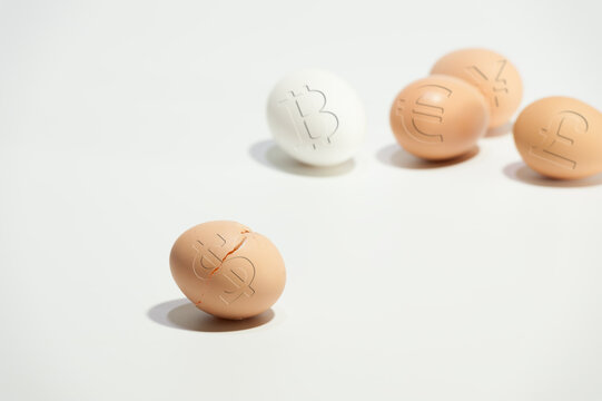 Broken egg with dollar symbol on the background of other eggs with world currency symbols