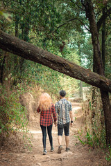 Couple walking through the forest back to back, outdoor excursion concept, day in the park couple holding hands