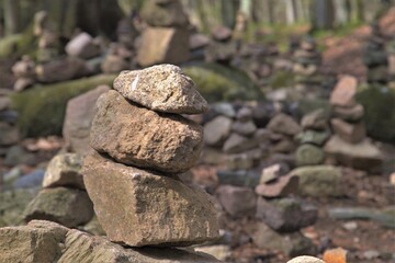 stack of three stones in foreground in a forest at a hiking trail