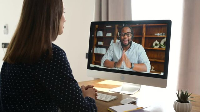 An African-American male employee, colleague or online tutor on the computer screen greeting, woman using laptop for video connection. Virtual conference, video call to coworker on the distance
