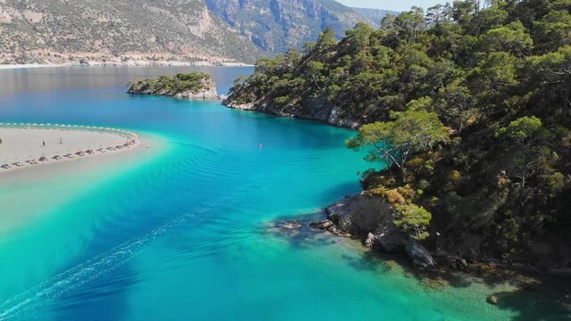 Aerial view of azure water in mediterranean sea in bay near Oludeniz, Turkey. Oludeniz is a resort village on the southwestern coast of Turkey. Boat sails through the purest turquoise water, sun