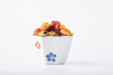 Homemade caramel cornflakes with cashews and raisins in a small bowl on white background