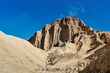 A family hike from Zabriskie Point in Death Valley national park in california. Huge sand dunes, terracotta mountains and hazy horizons are shining against clear blue sky in the midday sun.