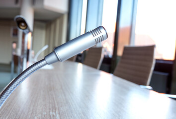 Weitwinkelige seitliche Nahaufnahme eines Mikrofons auf einem Tisch in einem Konferenzsaal oder...
