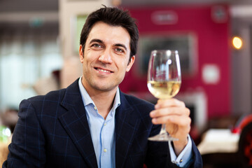 Handsome man holding a glass of white wine at the restaurant