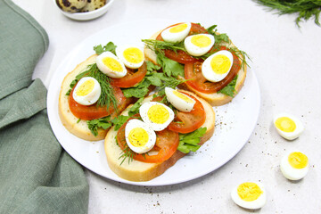 Fresh toast sandwiches with quail eggs, tomatoes and green herbs. Closeup. Top view. Copy space.