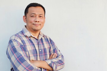 portrait of a man wearing Long sleeve shirt Standing with his arms folded, looking up at the camera.