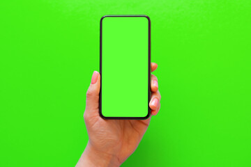 Person holding mobile phone with green screen on green background