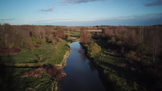 A Shallow River Surrounded By The Autumnal Plants On The Meadow aerial drone shot
