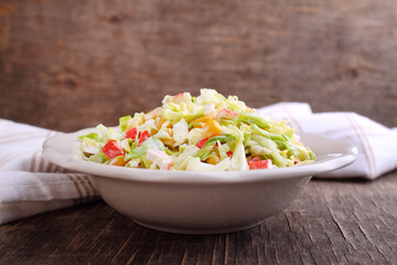 Salad of cabbage with grains corn and crab sticks in a plate on an old background.