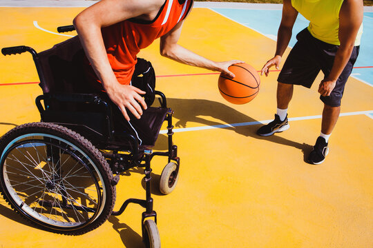 latin young man using wheelchair and playing basketball with a friend in America disability concept