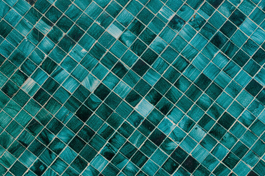 Minimalist textured monochrome background of old green teal mosaic tiles in horizontal display.