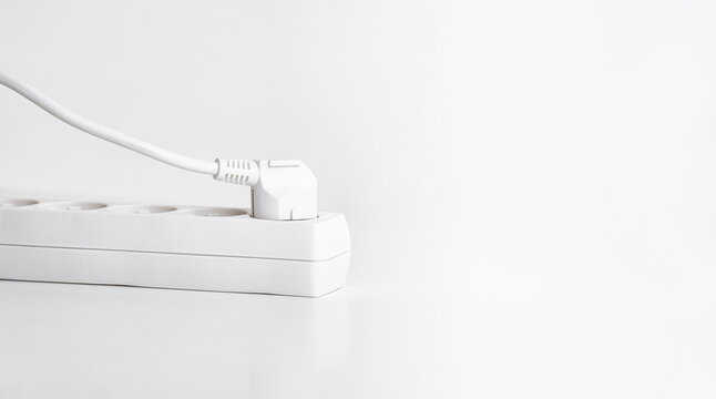 White power strip with plug on table and white background.