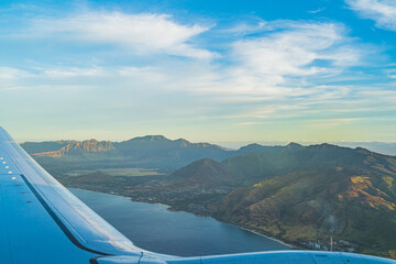 View of the tropical island of O'ahu from above over wing during golden hour - obrazy, fototapety, plakaty