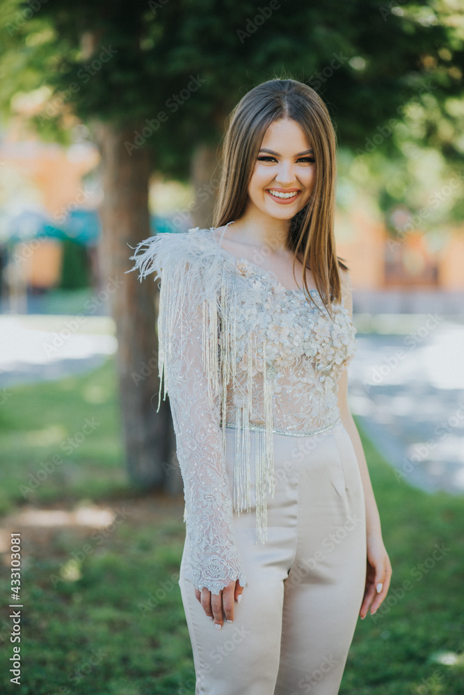 Sticker Vertical shot of a Caucasian female with beautiful jumpsuit posing outdoors