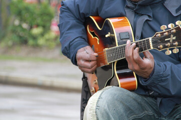 Fototapeta na wymiar A busking guitarist plays a tune on a semi-electric acoustic guitar in London