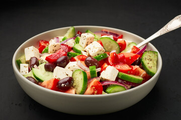 A big bowl of classic Greek salad on dark background