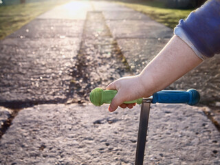 Boy's hand on steering wheel of scooter and road going into distance