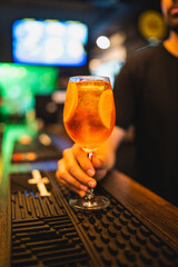 Closeup glass of spritz aperol cocktail decorated with orange at bright bar counter background with...