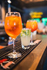 Close up aperol spritz, campari and mojito or caipirinha in counter bar with fruits lemon, orange,...