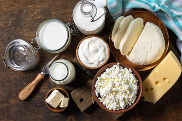 Set of different dairy organic products (milk, sour cream, cottage cheese, yogurt and butter) on a rustic wooden countertop. Top view flat lay.