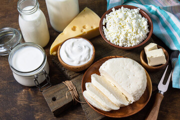 Set of different dairy organic products (milk, sour cream, cottage cheese, yogurt and butter) on a rustic wooden countertop.