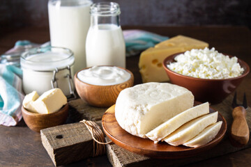 Set of different dairy organic products (milk, sour cream, cottage cheese, yogurt and butter) on a rustic wooden countertop.