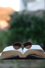 Open book and sunglasses in a garden. Selective focus.