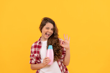 happy teen girl with long curly hair hold shampoo bottle, advert