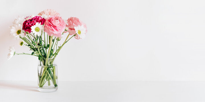 A bouquet of fresh spring flowers in a glass vase on a white table. Copy space for text.