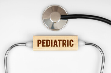 On the table is a stethoscope and a wooden plate with the inscription - PEDIATRIC